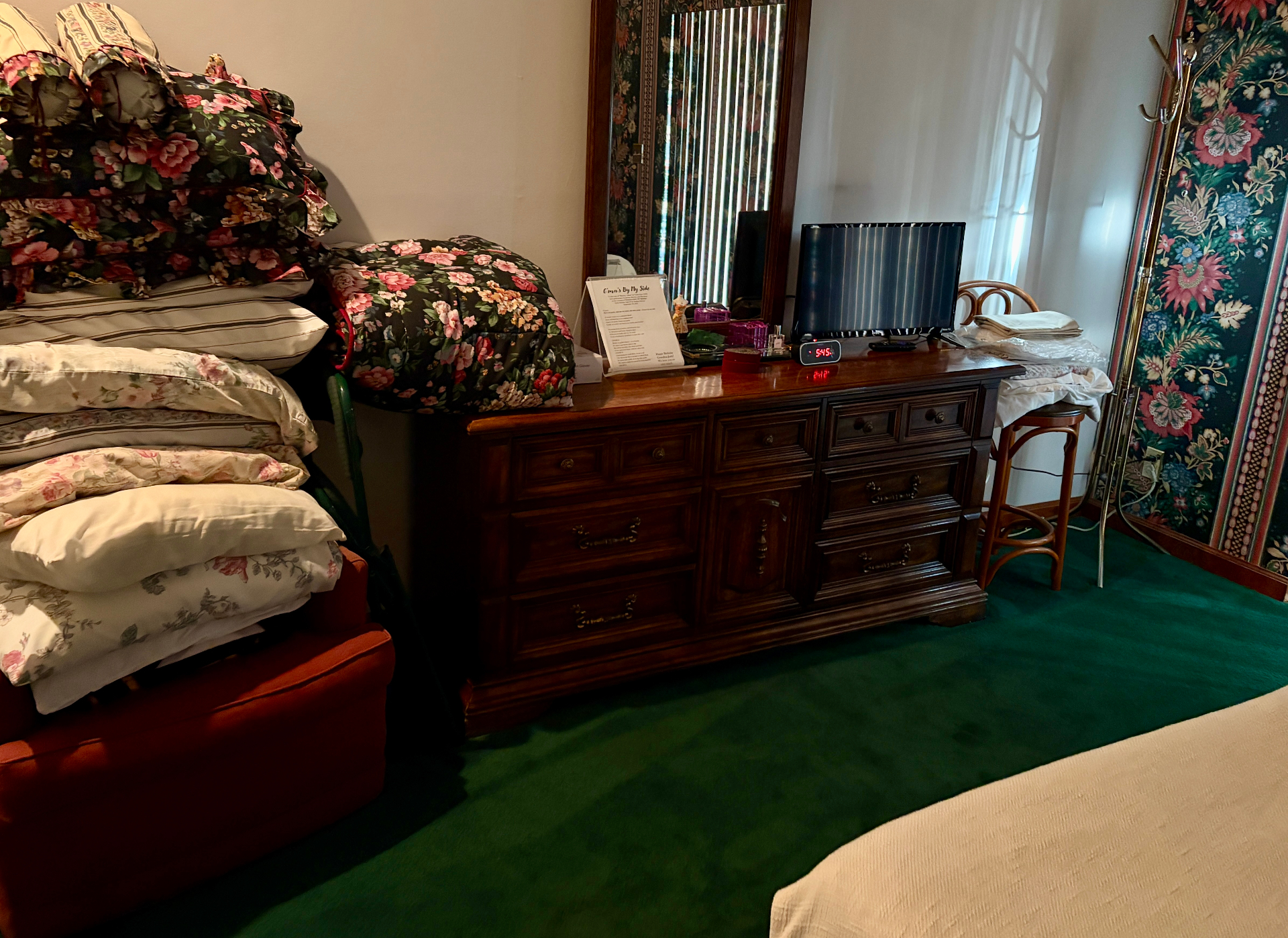 Bedroom with floral bedding, wooden dresser, and personal belongings during an estate cleanout in South Florida
