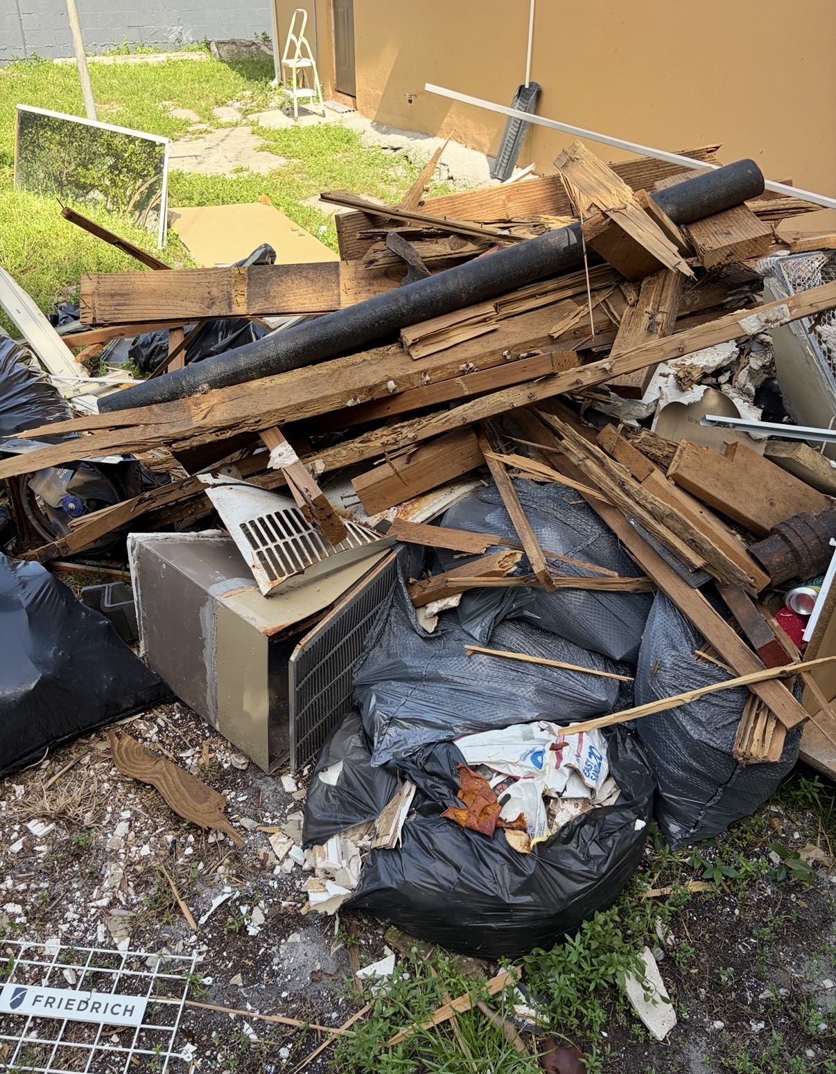Construction debris removal pile with lumber, drywall, and bagged waste at a South Florida job site